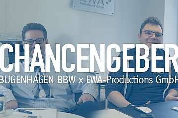 Zwei Männer sitzen in einem Büro, lächeln und posieren.