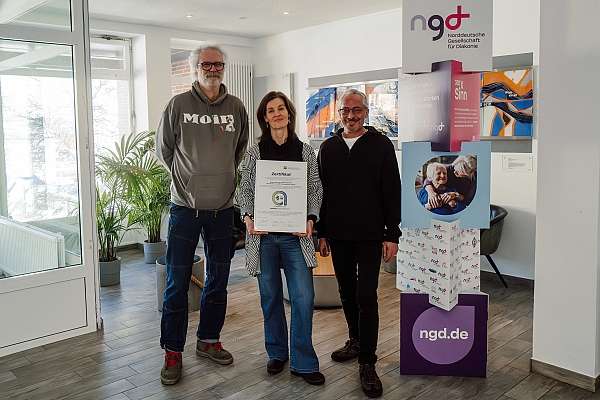 Drei Mitarbeitende halten ein Zertifikat in den Händen